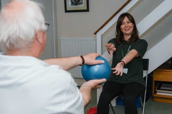 Client passing an exercise ball to his instructor