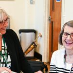 Staff member smiling and looking at happy Dementia Club client
