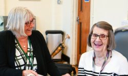 Staff member smiling and looking at happy Dementia Club client