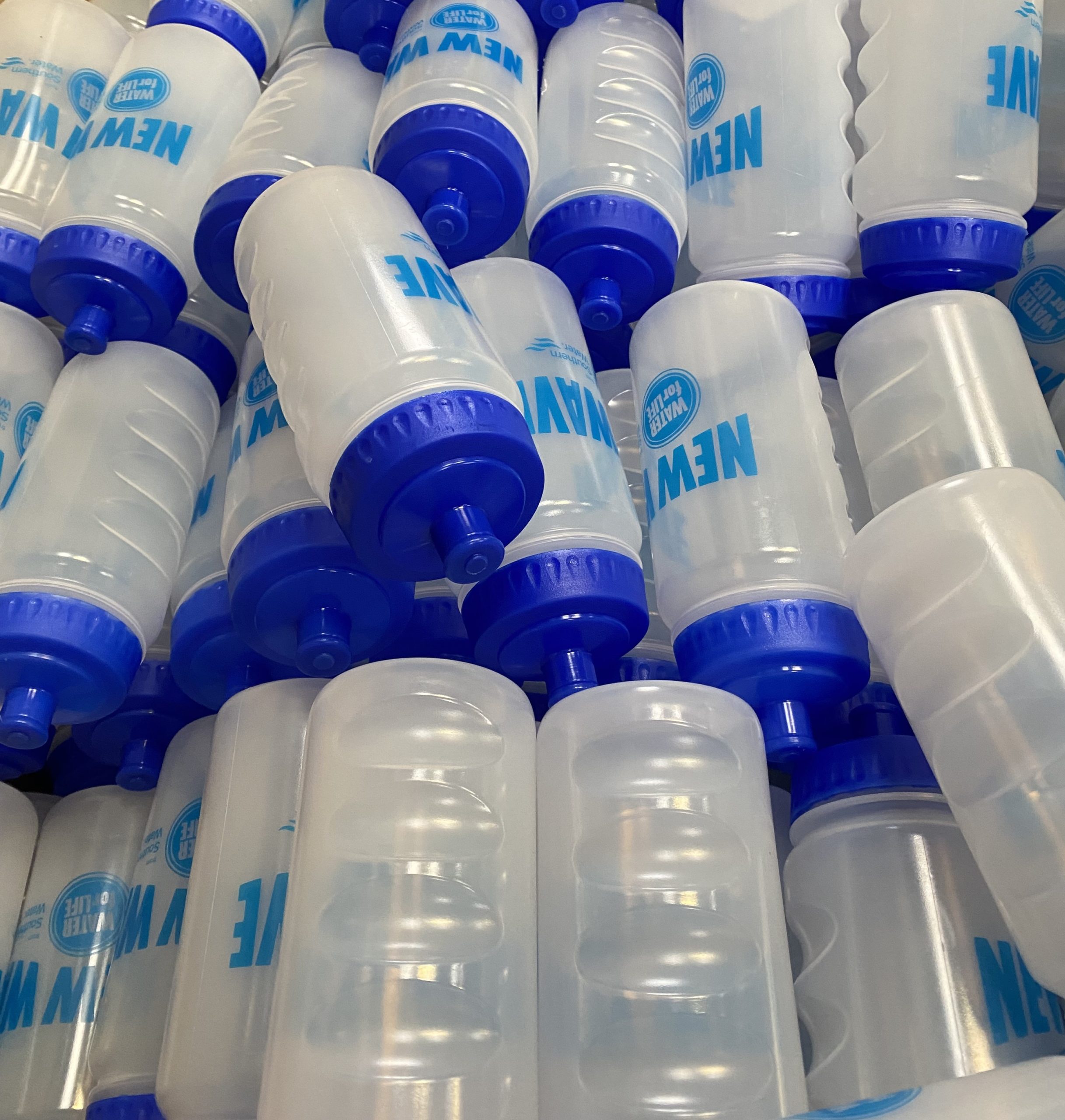 close up view of multiple clear water bottles with blue caps